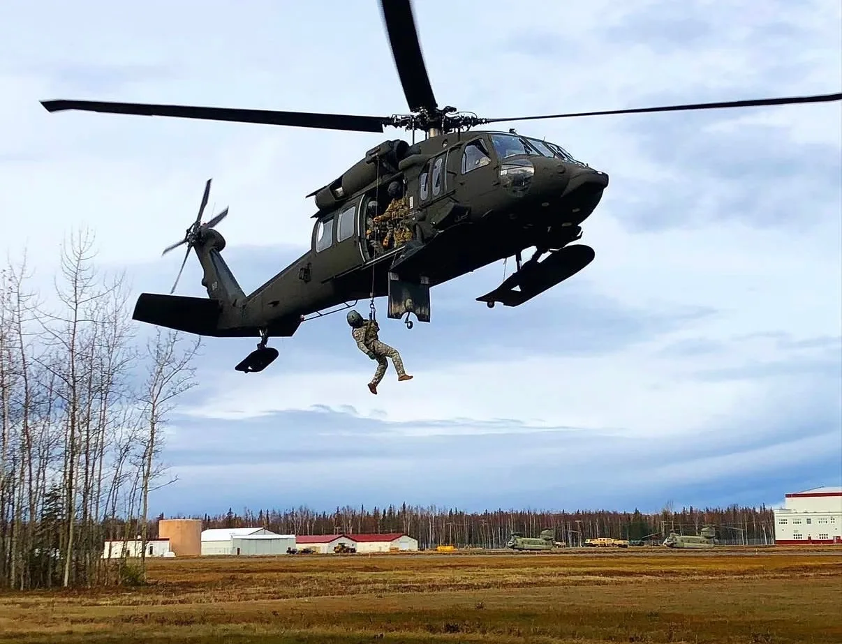 Alaska Army National Guard Black Hawk conducting a hoist rescue over an airfield